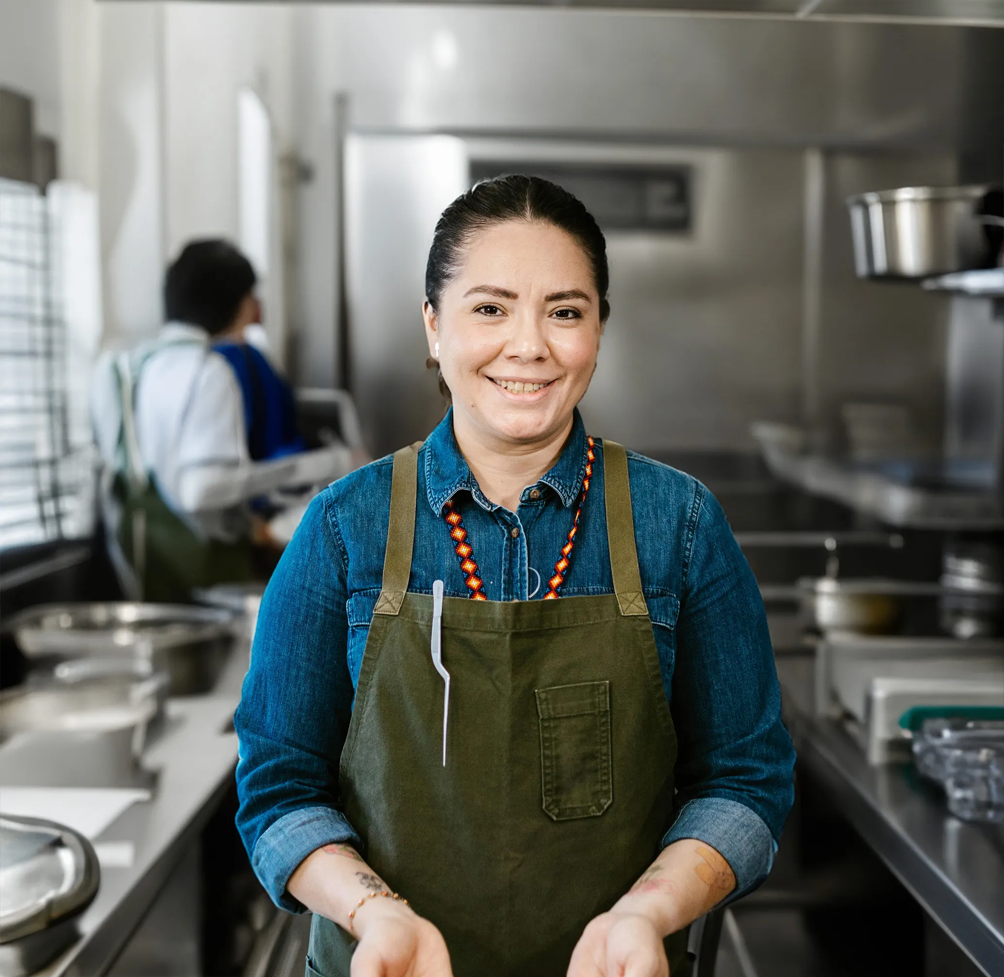 A woman smiling at the camera, standing in a kitchen